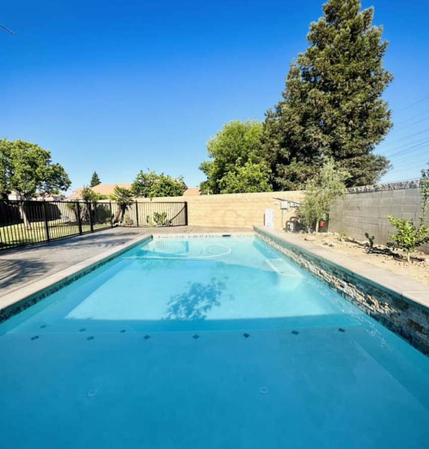 A crystal clear backyard residential pool in Kern County featuring a freshly applied, smooth plaster finish and professional tile repair completed by a licensed contractor.